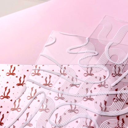 White decorative elements on a pink background with bow pattern