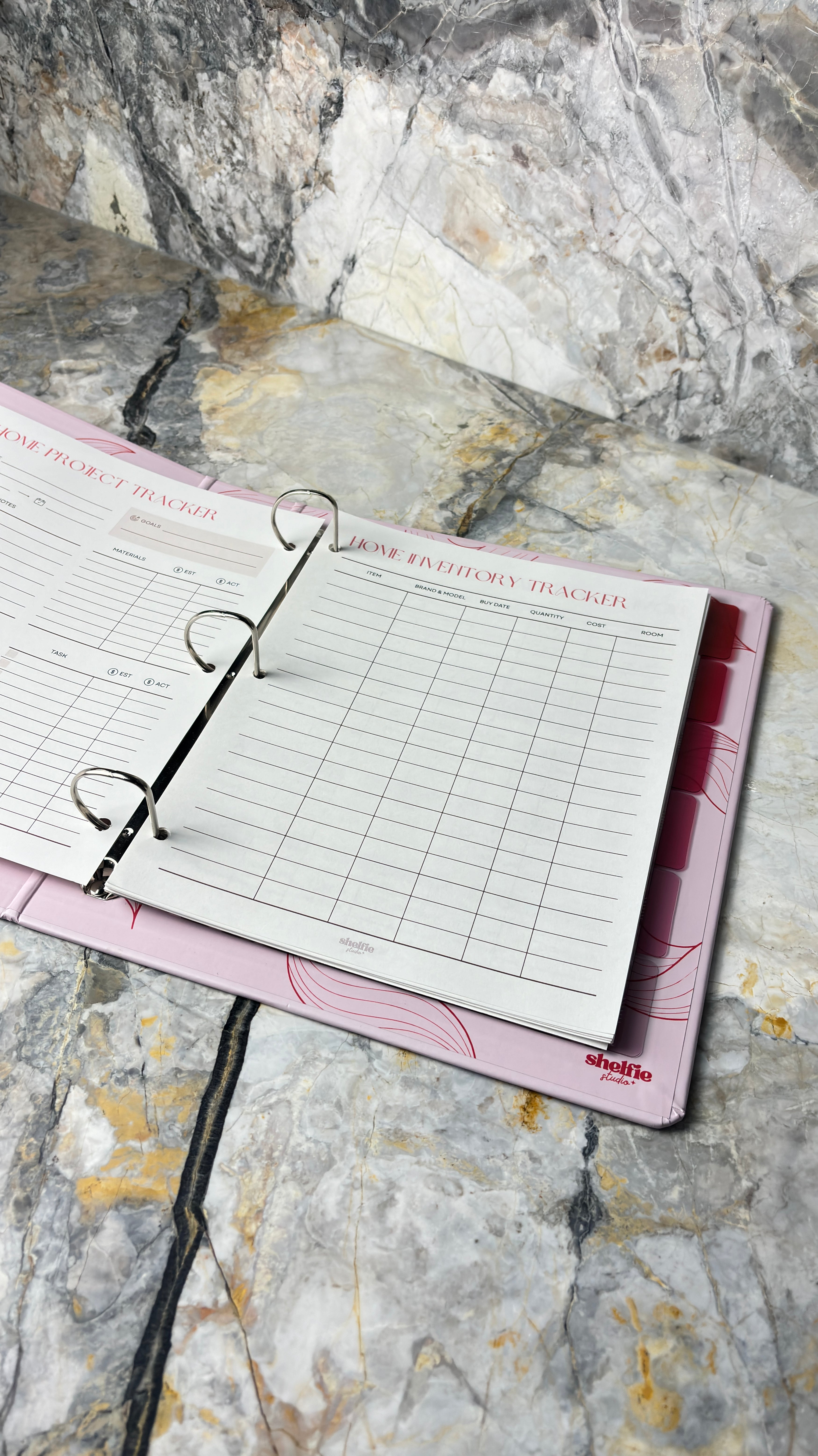 Pink planner with a ring binder on a marble surface