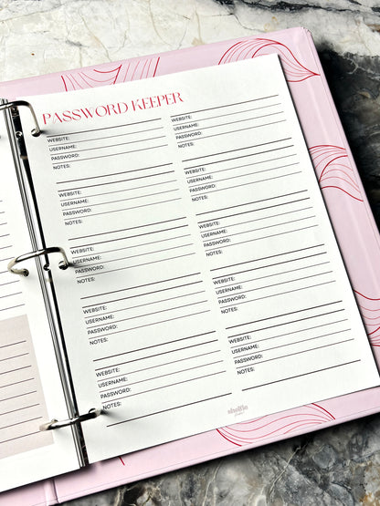 Password Keeper page in a planner with pink cover on a marble surface